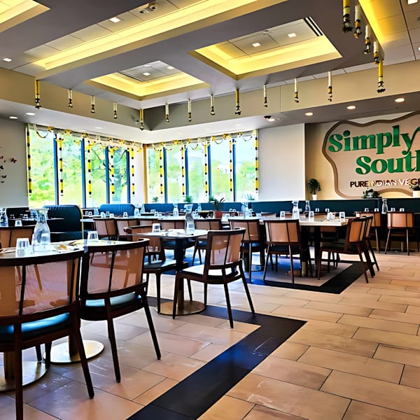 Simply South restaurant interior with set tables, blue booths, and a large logo on the wall.